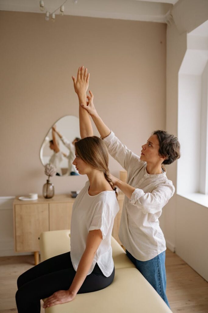 A therapist assists a woman with arm stretching during a session in a calming indoor setting.