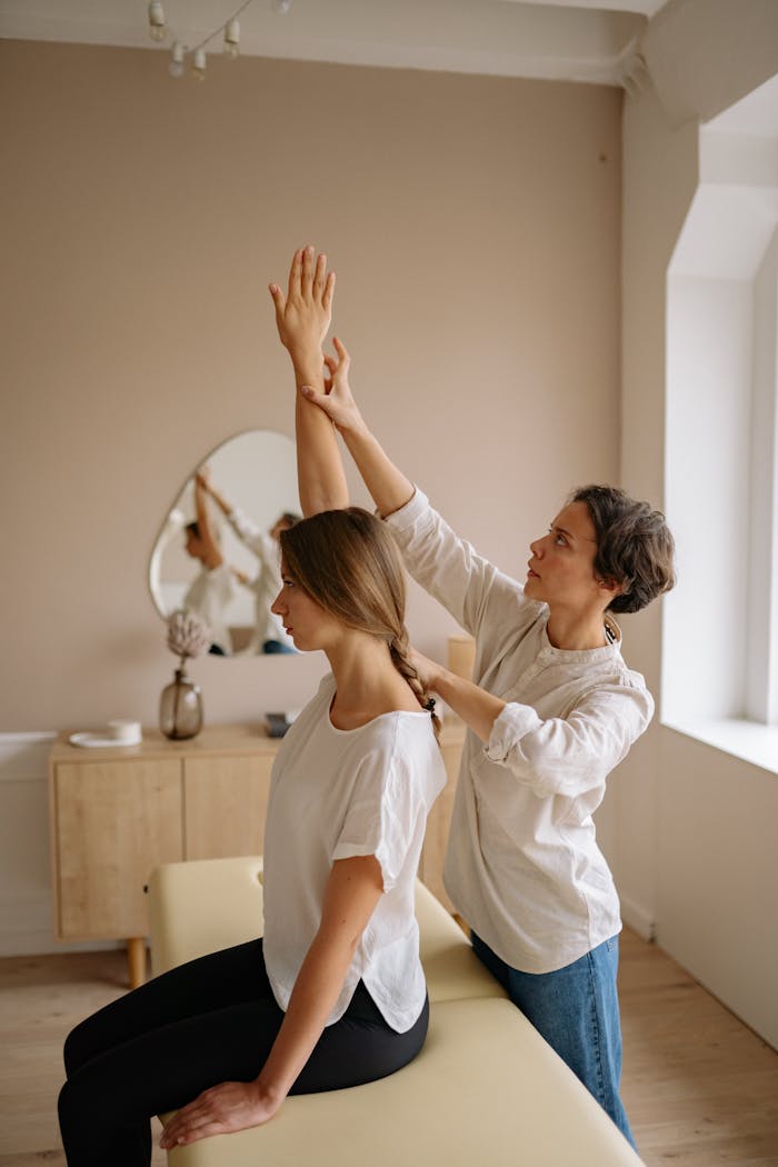A therapist assists a woman with arm stretching during a session in a calming indoor setting.