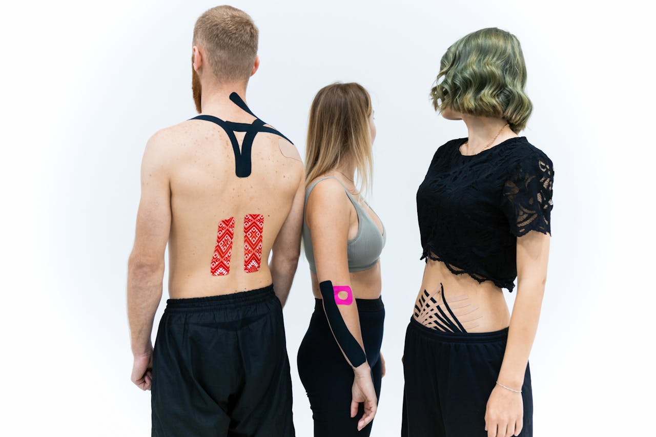 Three young adults demonstrating athletic kinesiology tape placement on bodies.